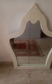 یک اینه دکوری کرمی روشن روی میزی به فروش میرسد