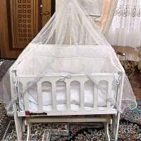 گهواره چوبی کنار تخت مادر کودک