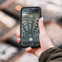 یک گوشی ایفون ۱۳ سفید در پارک شهرک فرهنگیان