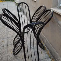 میز چوبی بیضی شکل با پایه فلزی فرفورژه بدون صندلی.