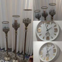 جا شمعی پایه بلند کنار سالنی با ساعت دیواری