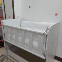 گهواره چوبی سفید کنار تخت