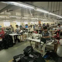 چرخکار خیاط و کارگر ساده در کارخانه تولید کیف