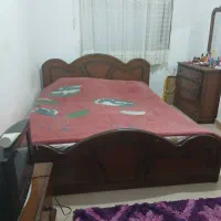 تخت دونفره و یک میز آرایش با آینه و یک پاتختی