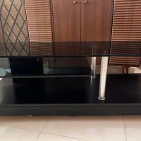میز تلویزیون شیک و کم‌جا با طبقات شیشه‌ای و چرخ
