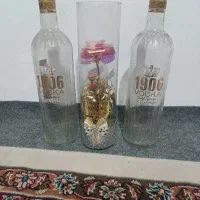 دو عدد بطری شیشهای با یک گل مصنوعی