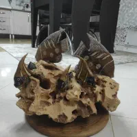 ماهی چوبی کار شده  روی سنگ رودخانه از جنس ماسه