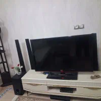 تلویزیون و میز تلویزیون و باند ها و ساعت ایستاده