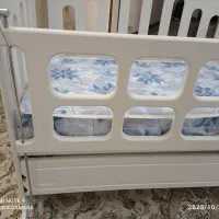 تخت کنار کادر گهواره ای بایک کالسکه سرمه ای