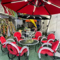 میز و صندلی فرفورژه با چتر سایبان آهن کنار برزنت