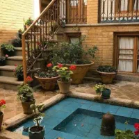 کلنگی با گلدان‌های زیبا در حیاط