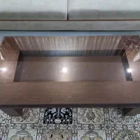 یک میز بزرگ ودوتا عسلی جلو مبلی