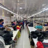 چرخکار خیاط و کارگر ساده در کارخانه تولید کیف