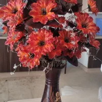 گلدان سفالی با گل‌های مصنوعی نارنجی
